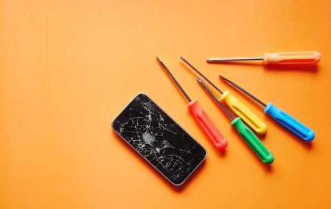 Top view of broken smart phone on color background