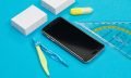 Two piles of white scratch paper, a pair of compasses, one ruler, a yellow text marker and black smartphone on azure background isolated